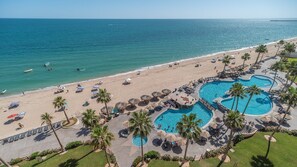 Ein Resort mit Strand, Poolbereich und Meerblick.