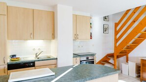 Una cocina compacta con armarios de madera, lavavajillas integrado y una escalera de madera.