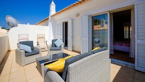 A rooftop terrace with wicker furniture, a glass table, and sliding glass doors leading to a bedroom. - 6a Fabrica velha Beautiful house + pool walking distance to beach (Carvoeiro)