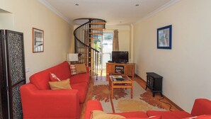 A living room with a red sofa, a wooden coffee table, a TV, and a fireplace. - 6a Fabrica velha Beautiful house + pool walking distance to beach (Carvoeiro)