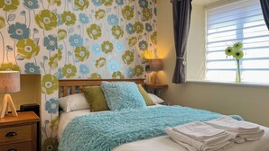 Une chambre à coucher avec un lit, des tables de chevet, une lampe et une fenêtre avec des rideaux.