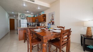 Une cuisine spacieuse avec des meubles en bois, une grande horloge et un coin repas comprenant une table et des chaises en bois.