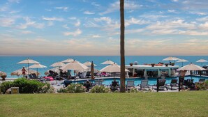 Un espace aménagé au bord de la piscine, avec des chaises longues et des parasols, offrant une vue sur l’océan.