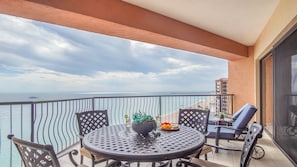 A balcony with a round table, chairs, and a potted plant.