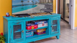 Un mueble turquesa con juegos de mesa y una pintura de una playa.