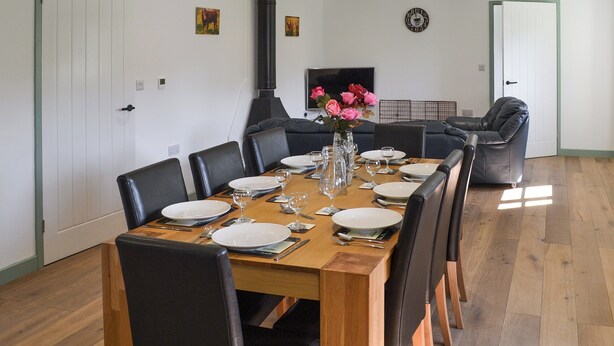 Un coin repas avec une table en bois dressée pour six personnes, entourée de chaises noires.