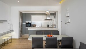 Una cocina moderna con electrodomésticos de acero inoxidable, una isla central y un comedor con mesa y sillas.