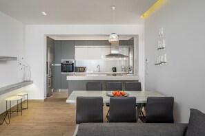 A modern kitchen with stainless steel appliances, a central island, and a dining area with a table and chairs.