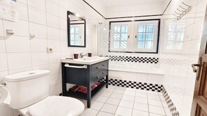 Une salle de bain comprenant des toilettes, un lavabo, un meuble-lavabo et une baignoire.