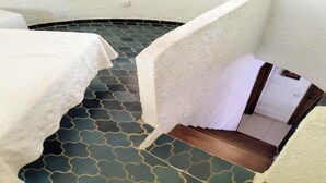 Una scala con un pavimento decorato che conduce a una stanza con una parete bianca e strutturata.