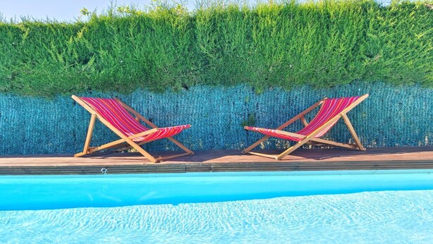 Une piscine avec deux chaises longues à rayures.