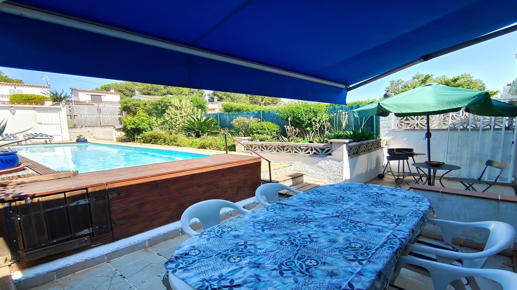 Un espace aménagé au bord de la piscine, comprenant un coin salon couvert, un jacuzzi et un barbecue.