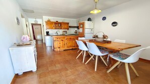 Une cuisine avec des meubles en bois, une table à manger avec des chaises et un réfrigérateur.