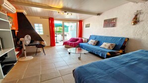 Un salon avec un canapé, une petite table, un ventilateur et un barbecue.