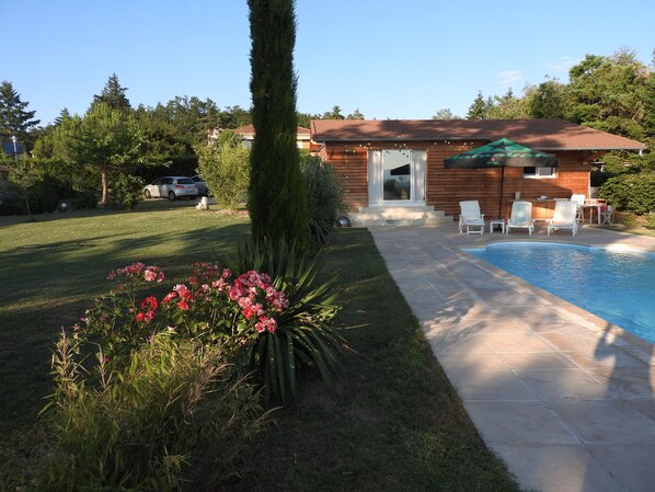 Ein Wohnhaus mit Swimmingpool, einer Terrasse und Gartenmöbeln sowie einem gepflegten Garten.
