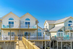 Een strandpand met meerdere tweelaags gebouwen, elk voorzien van een balkon met een witte railing.