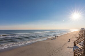 A beach with a wooden boardwalk and a clear sky.