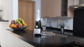 Un comptoir de cuisine avec une bouteille de vin, un verre et un bol de fruits.