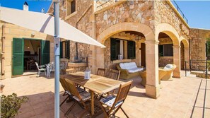 Relax on the patio surrounded by stone walls and enjoy the shade under a white umbrella.