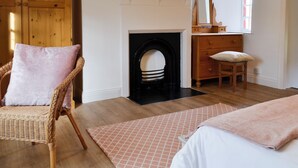 A bedroom with a fireplace, wooden furniture, and a window. - 2 bedroom accommodation in Greenwell, near Brampton (Greenwell, near Brampton)