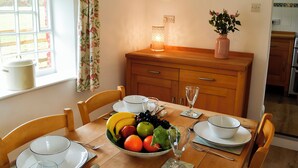 A dining table set with plates, bowls, cutlery, and a fruit bowl. - 2 bedroom accommodation in Greenwell, near Brampton (Greenwell, near Brampton)