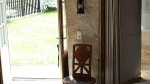 A room with a table covered by a patterned tablecloth, a chair, and a door leading outside. - Logis in the chateau enclosure (Paizay-Naudouin-Embourie)