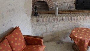 A cozy room with a stone fireplace, a sofa, a small table, and a decorative vase. - Logis in the chateau enclosure (Paizay-Naudouin-Embourie)