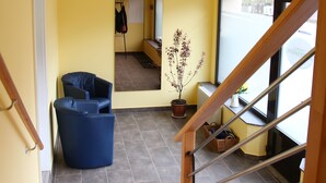 A modern interior with a staircase, a blue chair, a potted plant, and a view through a window. - Ferienhaus Landeskrone (Dresden)