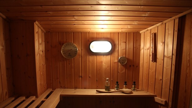 A wooden sauna with benches, a small window, and a wooden ceiling. - Ferienhaus Landeskrone (Dresden)