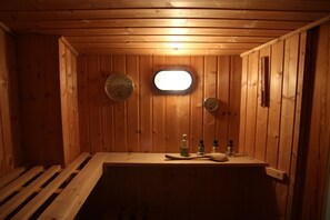 Eine Holzsauna mit Bänken, einem kleinen Fenster und einer Holzwanddecke.