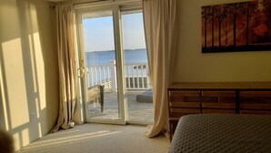 Un dormitorio con un gran ventanal corredera que da a un balcón con vistas al mar.