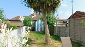 A backyard with a palm tree, a shed, and a fence. - Repton Cottage -  a cottage that sleeps 5 guests  in 2 bedrooms (Cromer)