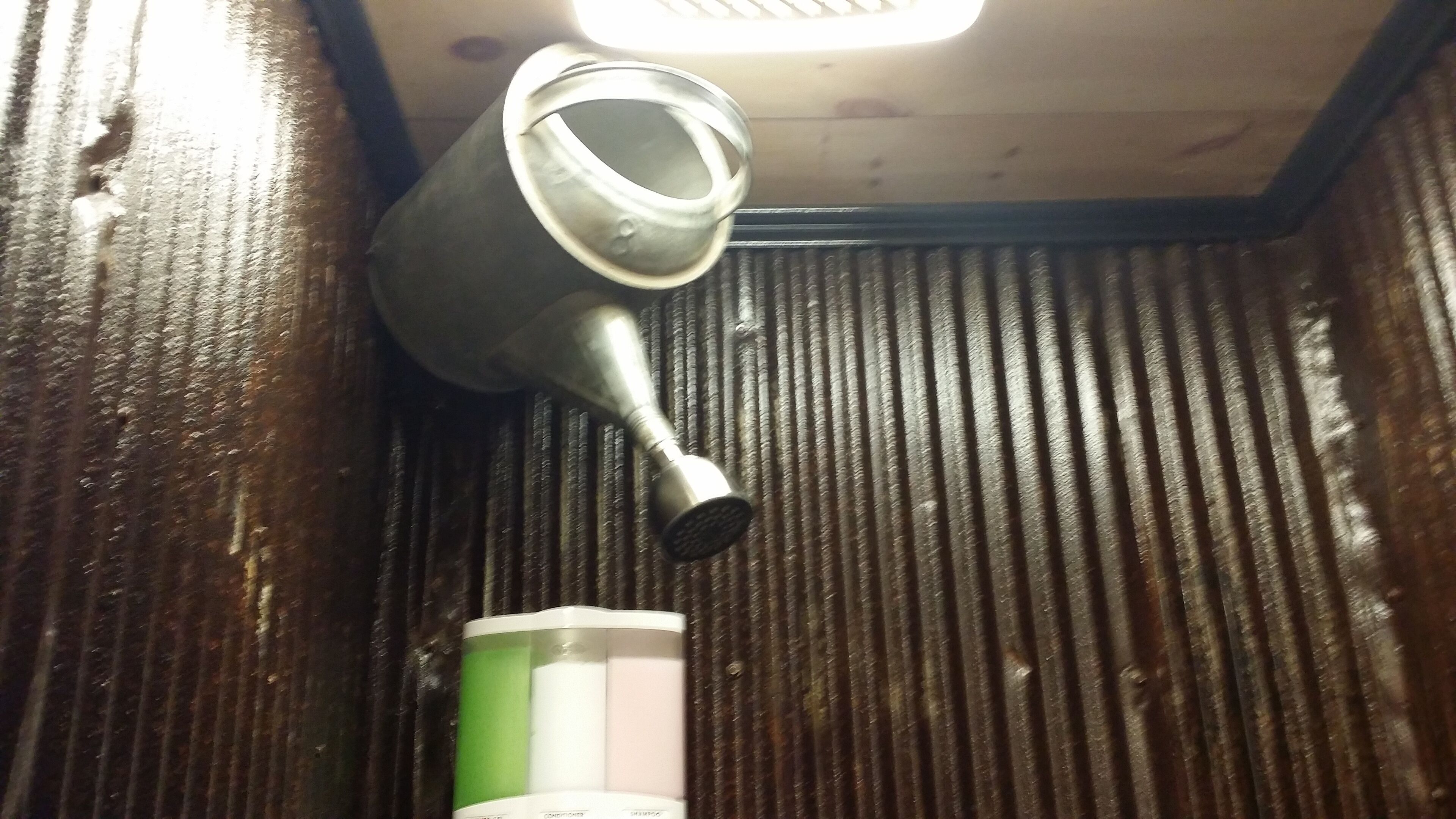 A metallic object, possibly a faucet, attached to a wooden surface with a corrugated texture.