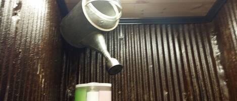 A metallic object, possibly a faucet, attached to a wooden surface with a corrugated texture.