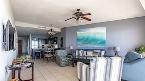 A spacious living room with a large sofa, a dining area, and a kitchen in the background. - Sonoran Sea West 407 Ocean View Condo (Puerto Peñasco)