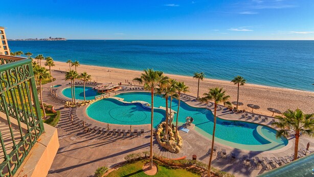 A resort with a large pool area, palm trees, and a beach view. - Sonoran Sea West 407 Ocean View Condo (Puerto Peñasco)