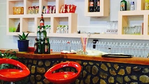 A bar area with stools, shelves stocked with snacks, and bottles of beverages. - Villaggio shehu (Orikum)