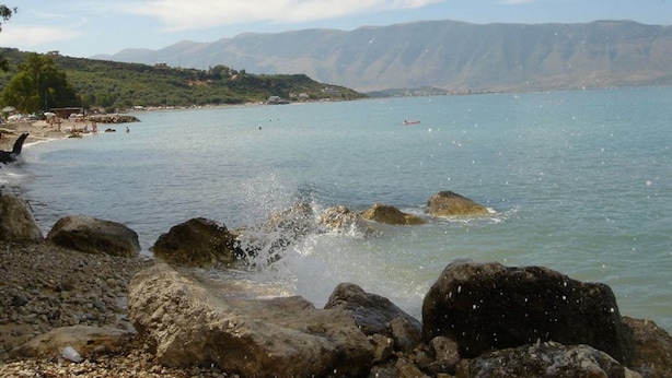 A rocky shoreline with clear water and distant mountains. - Villaggio shehu (Orikum)