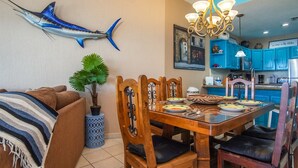 Un comedor con una mesa y sillas de madera, un candelabro, una planta en maceta y un adorno de pez montado en la pared.
