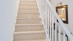 En trappe med hvide gelændere og beige trin, der fører til en etage ovenpå.
