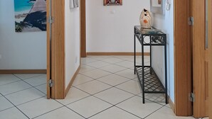 A hallway with tiled flooring, wooden doors, and wall-mounted artwork. - T3, espaçoso, wifi, a/c, junto à praia! (Albufeira)
