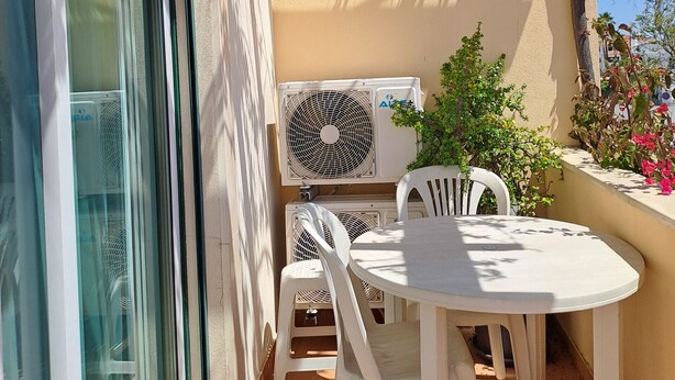 An outdoor patio with a table and chairs, an air conditioning unit, and a view of the sky. - T3, espaçoso, wifi, a/c, junto à praia! (Albufeira)