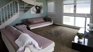 A living room with a staircase, a sofa, a coffee table, and a view through large windows. - Duplex San Luis - 1ªline beach, incredible view garage by Egona (Zarautz)