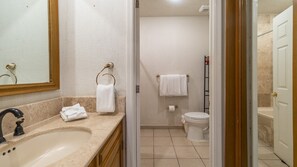 A bathroom with a sink, toilet, and shower area.