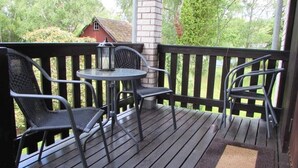 A wooden deck with a round table and two chairs, a lantern, and a doormat. - House in Småland, ideal for children and dog owners with hiking trail at the house (Uppvidinge S)