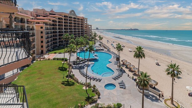 Een resort met een groot zwembad, strand en uitzicht op de oceaan.