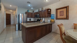 A kitchen with a central island, stainless steel appliances, wooden cabinets, and a water dispenser.