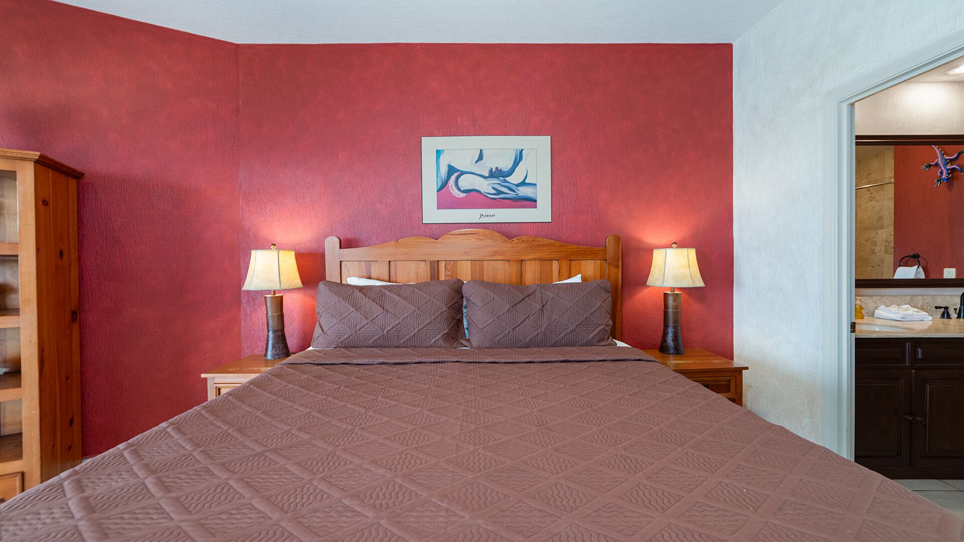 Ein Hotelzimmer mit einem großen Bett, zwei Nachttischlampen, einem Holzkopfstück und einem Gemälde an der Wand.