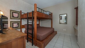 A bunk bed room with a desk and framed pictures on the wall.