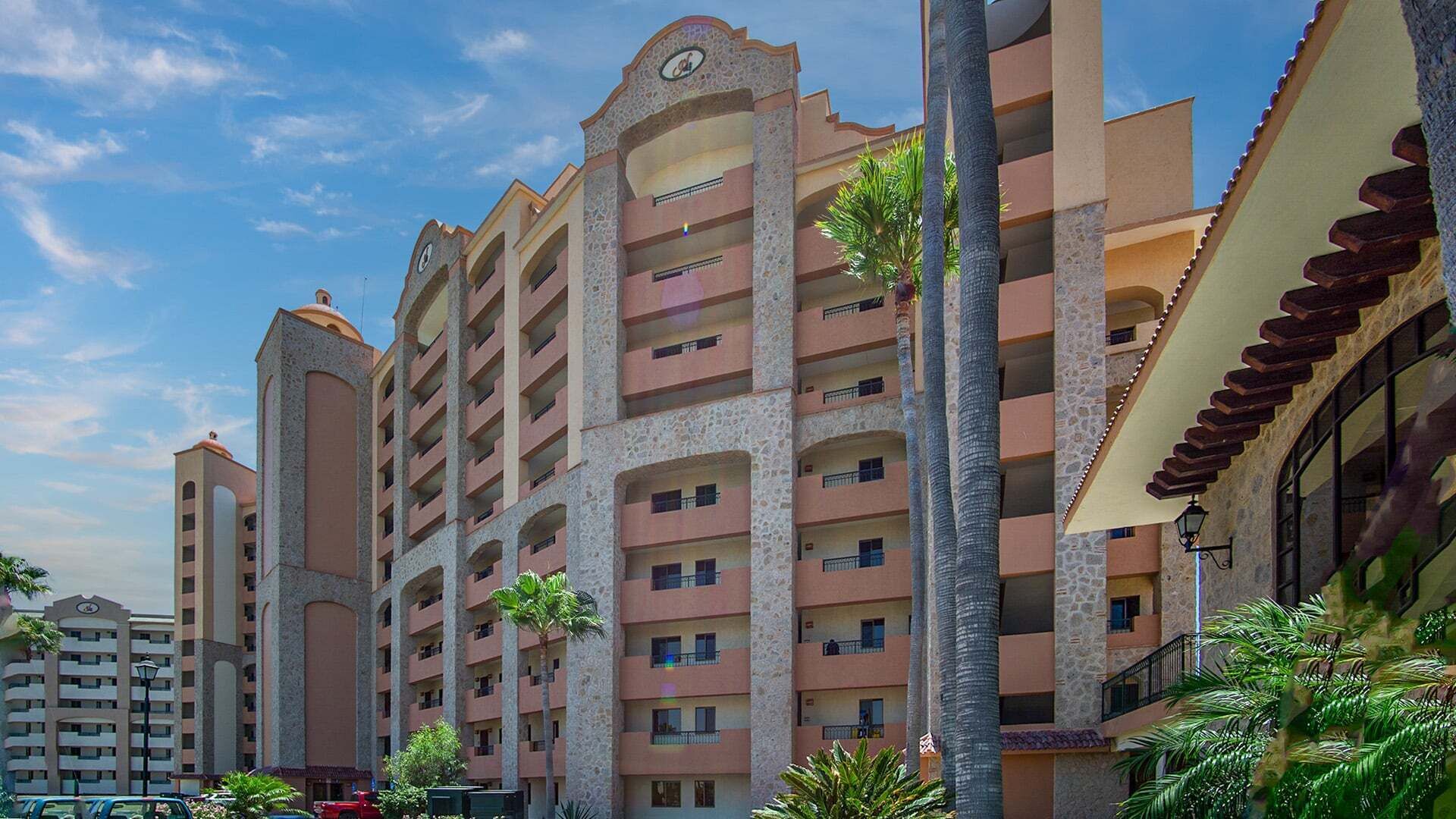 A multi-story hotel with balconies, a central atrium, and palm trees.